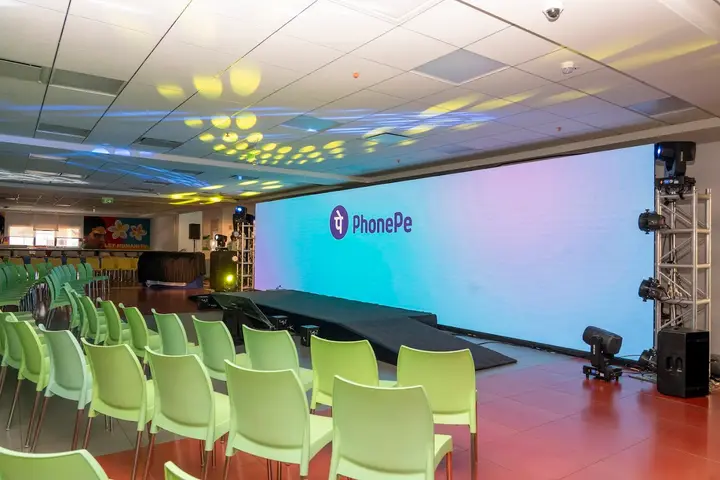 PhonePe event hall with an LED wall, stage lighting and rows of green chairs