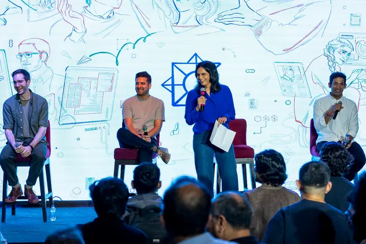 Panel discussion on stage in front of an illustrated backdrop