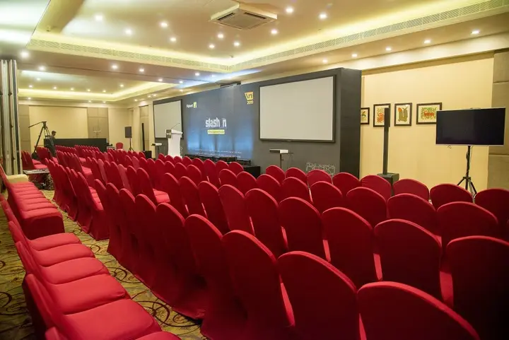 Conference hall with red chairs and twin projection screens