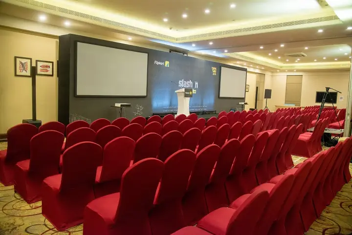 Wide view of a conference hall with red seating set for a session