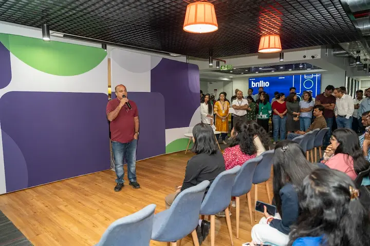 Speaker addressing a standing audience at a Brillio town hall
