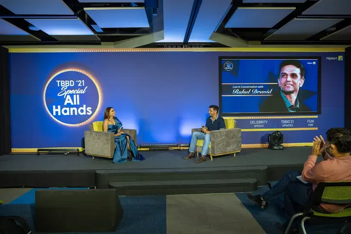 Fireside chat on a blue-lit stage at a Special All Hands event